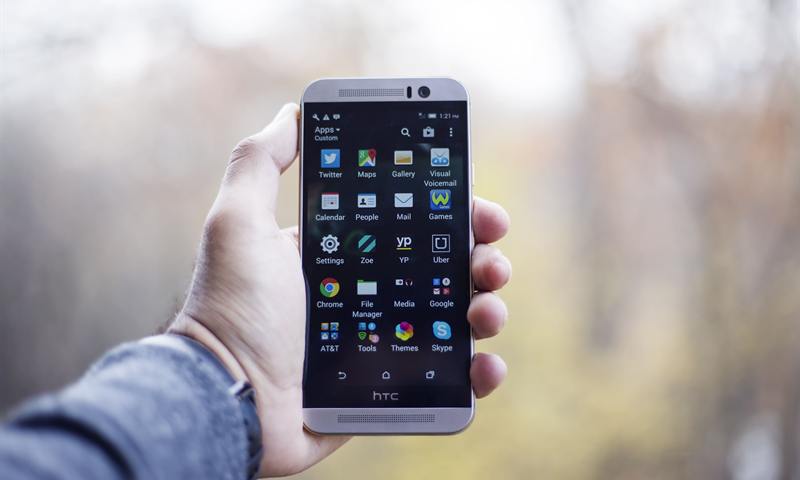 Main tenant un smartphone affichant un écran d'applications